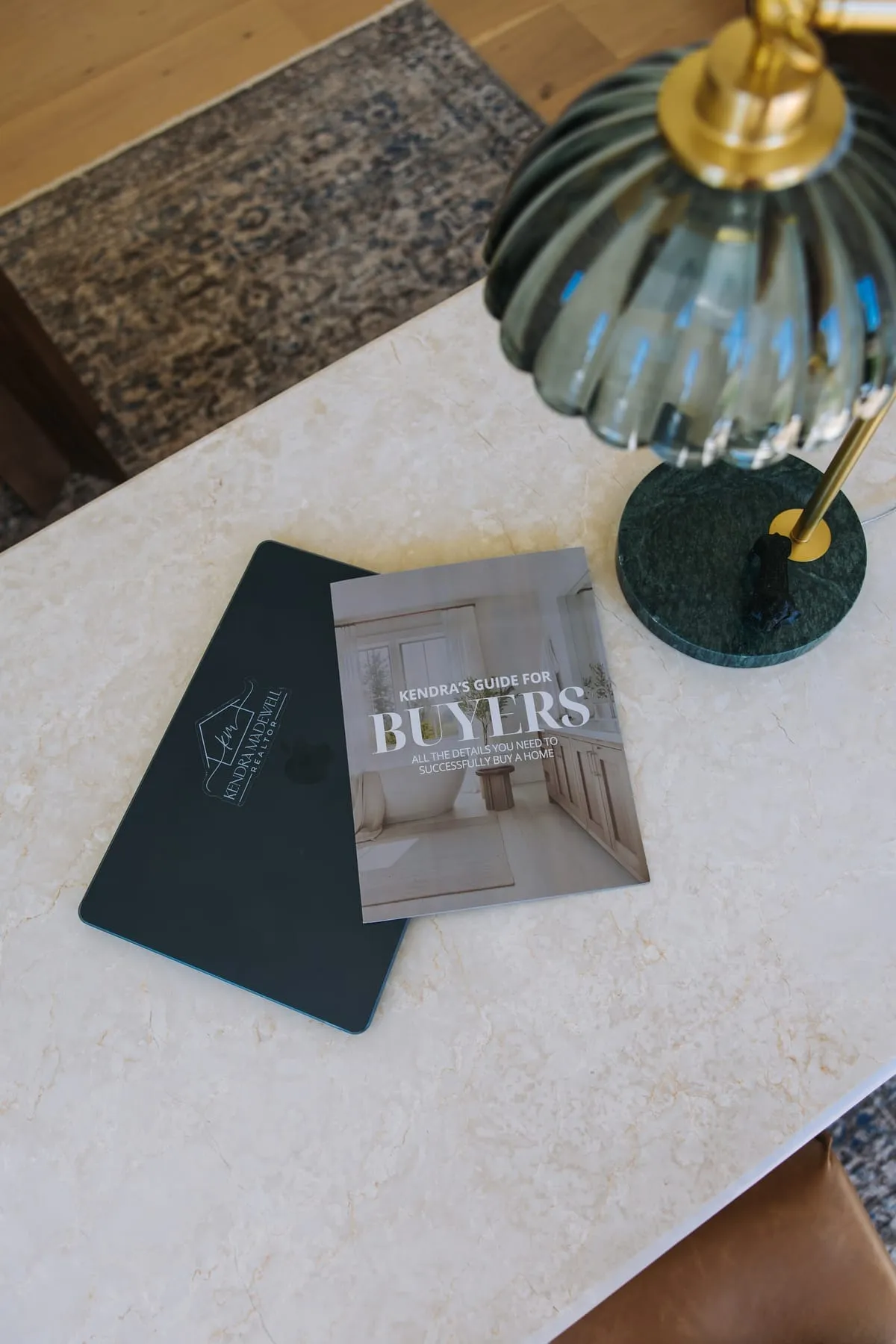 Printed copy of Kendra's Guide for Buyers, a free guide to buying a home in Northwest Arkansas, beside a Kendra Madewell branded folder
