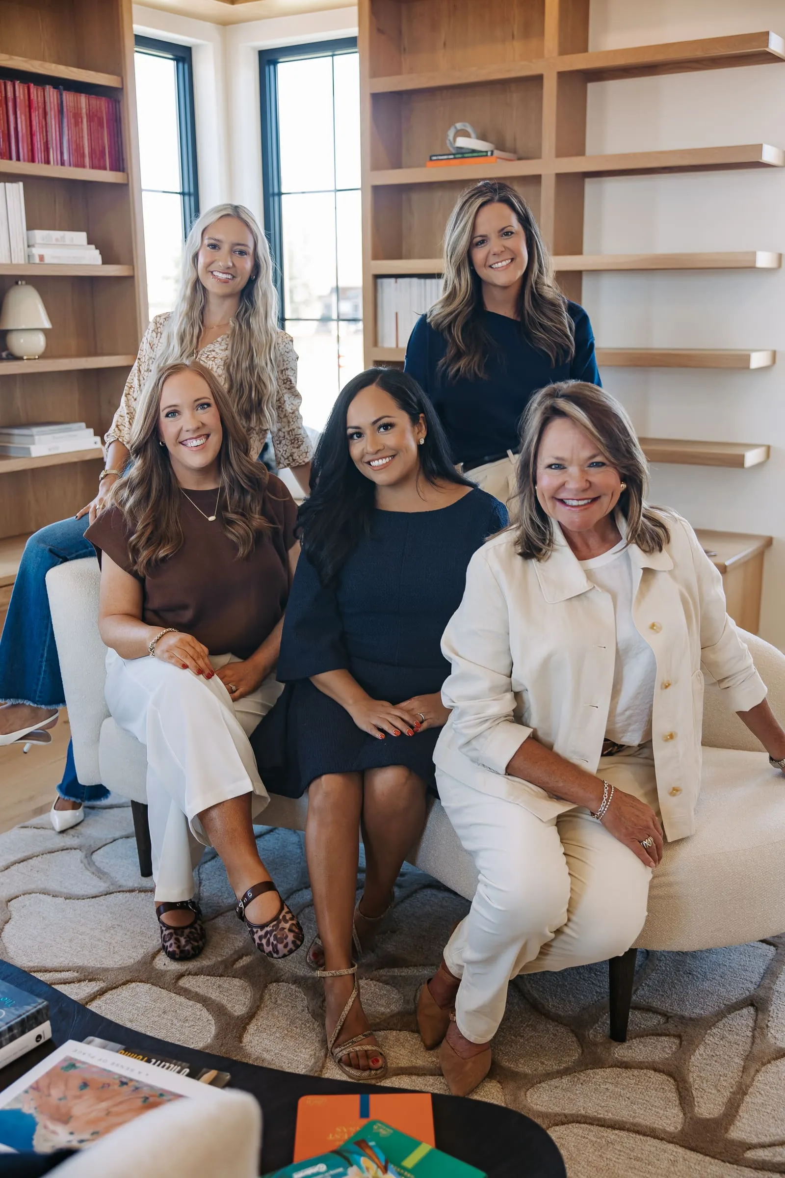 Kendra Madewell (front left, in brown) with fellow Northwest Arkansas real estate agents in a bright, book-lined living room